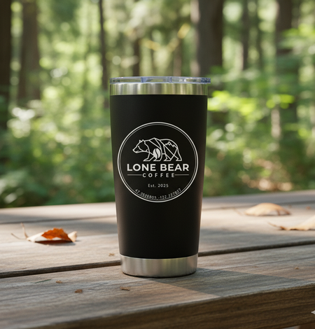 Black tumbler with 'Lone Bear Coffee' logo on a wooden surface with a forest background