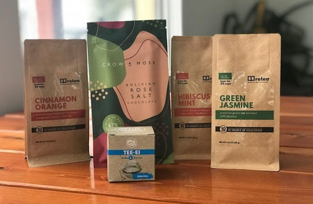 Lone Bear Backcountry Comfort Bundle gift box showing Retea tea, stainless steel infuser, and Crow & Moss chocolate bar on a wooden surface.