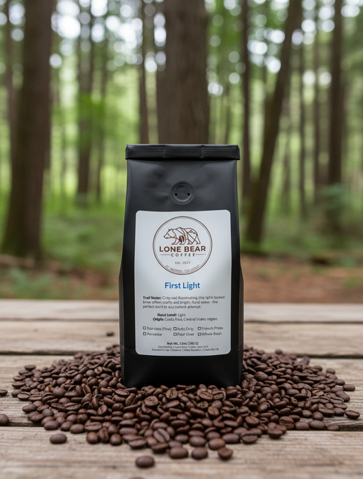 Lone Bear Coffee bag labeled 'First Light' surrounded by coffee beans on a wooden surface with a forest background