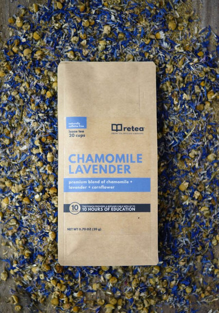 Retea Chamomile Lavender herbal tea bag surrounded by dried chamomile and blue cornflowers. This pouch provides 10 hours of education to a refugee child.